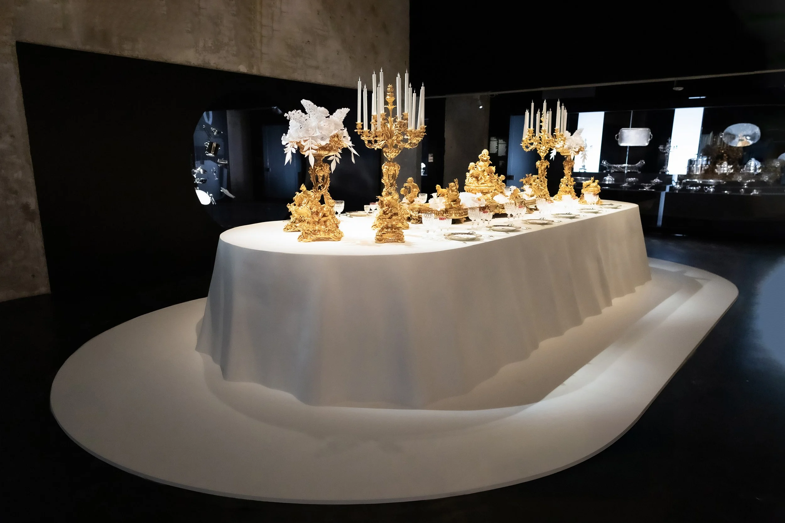 Exhibition scenography featuring white paper floral installations on a banquet table for Christofle at the Musée des Arts Décoratifs, Paris.