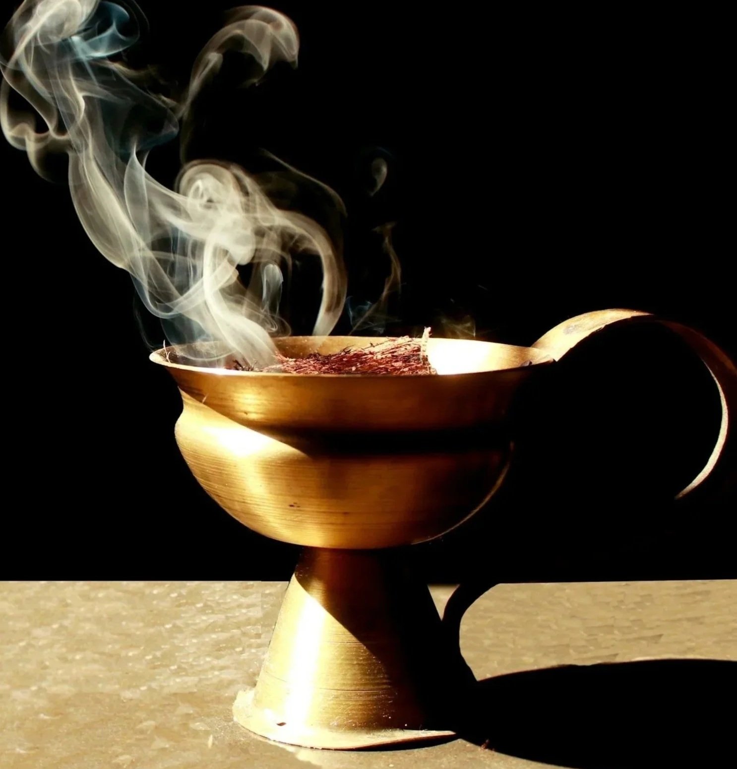 incense burning in a gold cup with black background