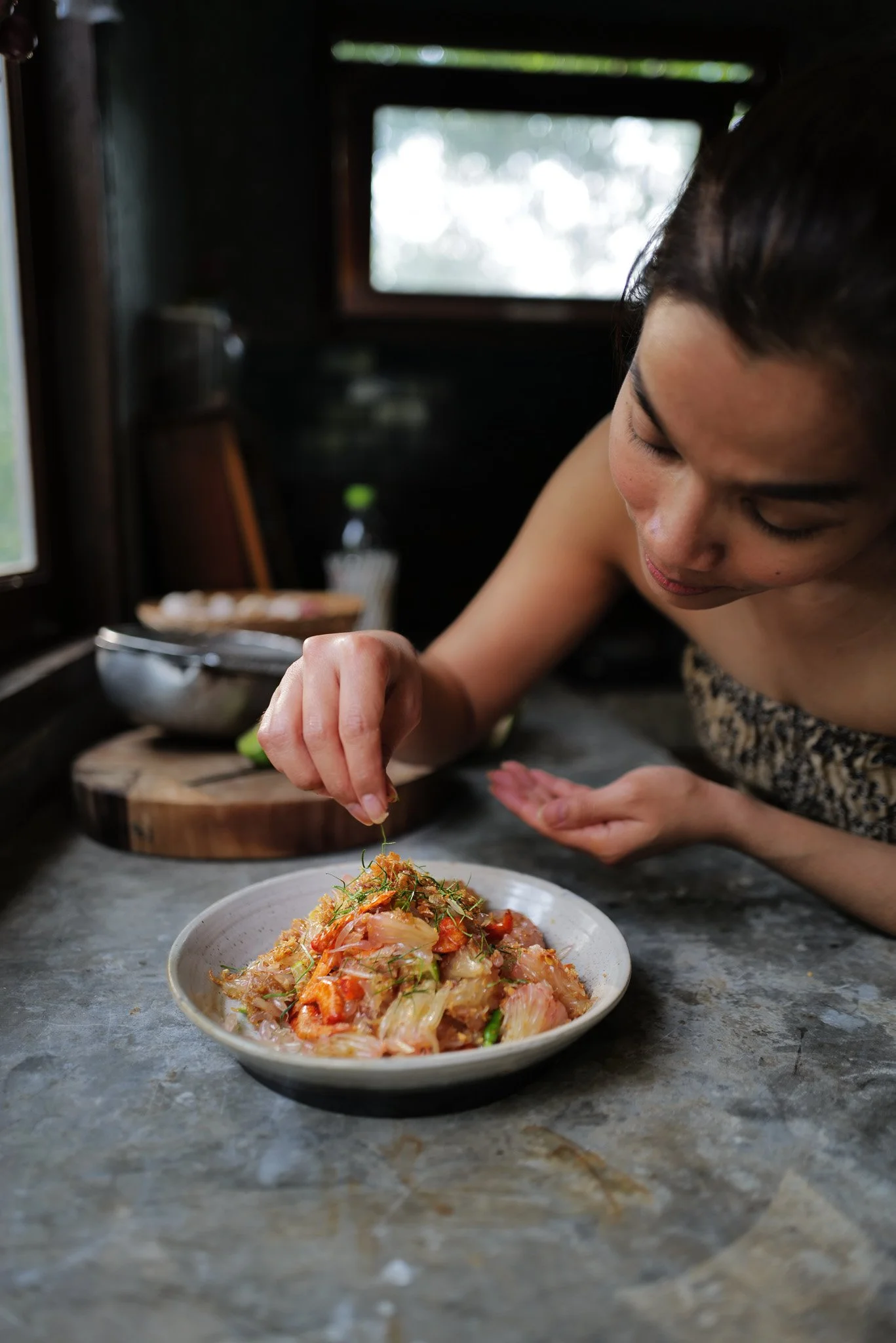 Amy plating a Thai pomelo salad with fresh herbs and dried shrimp.