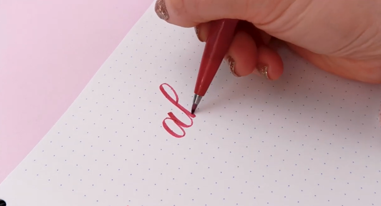 A Rhodia Dot Pad open on a flat surface, showing the smooth vellum paper with a subtle dot grid pattern used as a calligraphy practice pad.