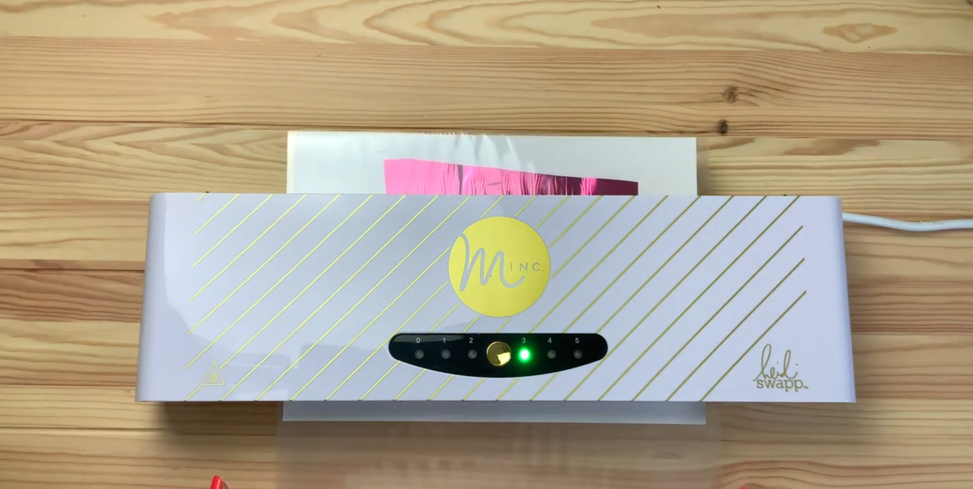 Feeding foil print through Minc foil machine to apply heat and bond foil to toner