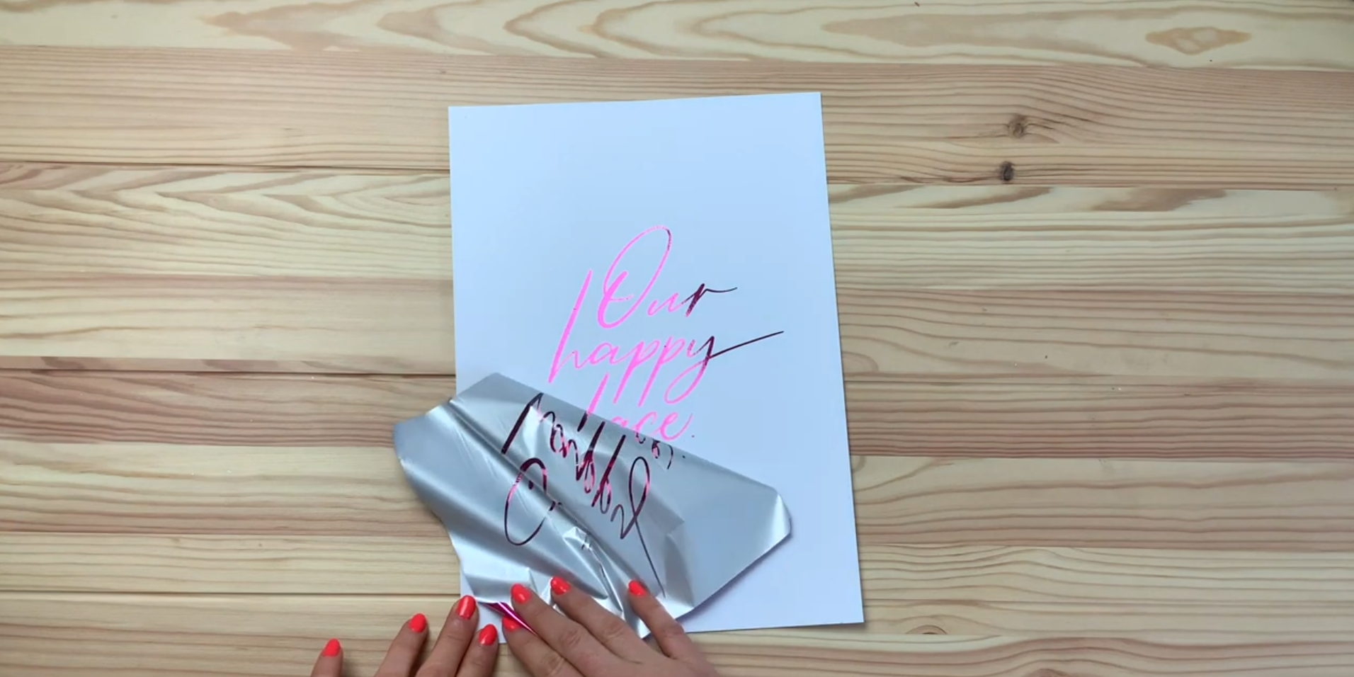 Peeling back toner reactive foil to reveal shiny metallic calligraphy design