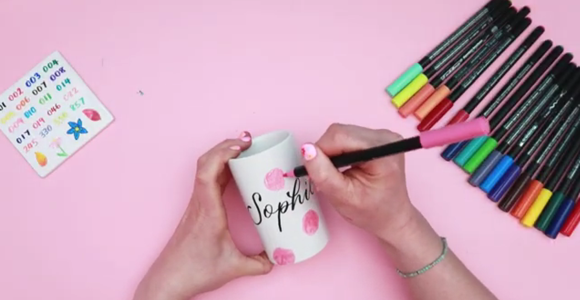 Painting loose pink circular shapes on ceramic to form base of rose flowers using brush pen