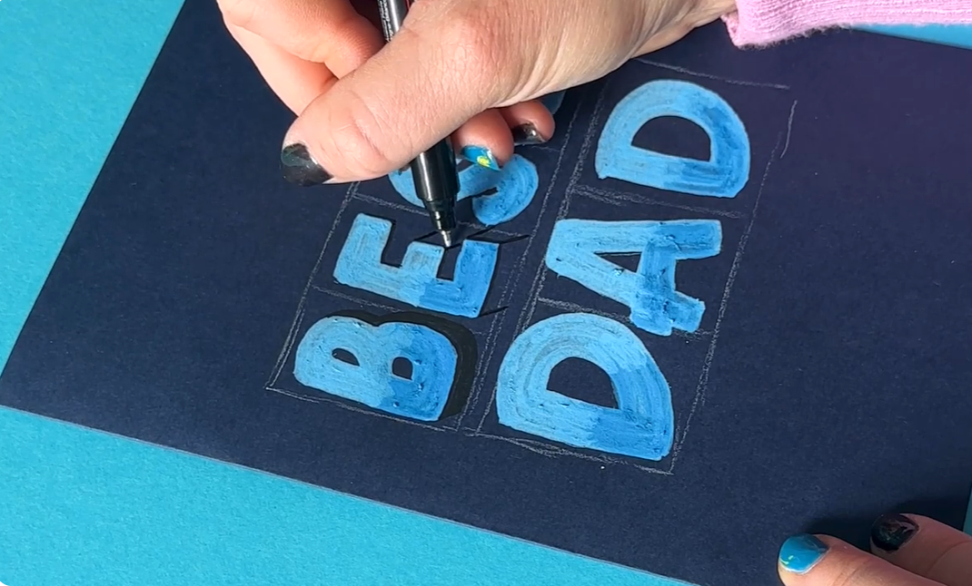 A fine-tipped black Posca pen adding 45-degree angle drop shadows to the bottom and right edges of bold blue hand-lettered text on dark card stock.