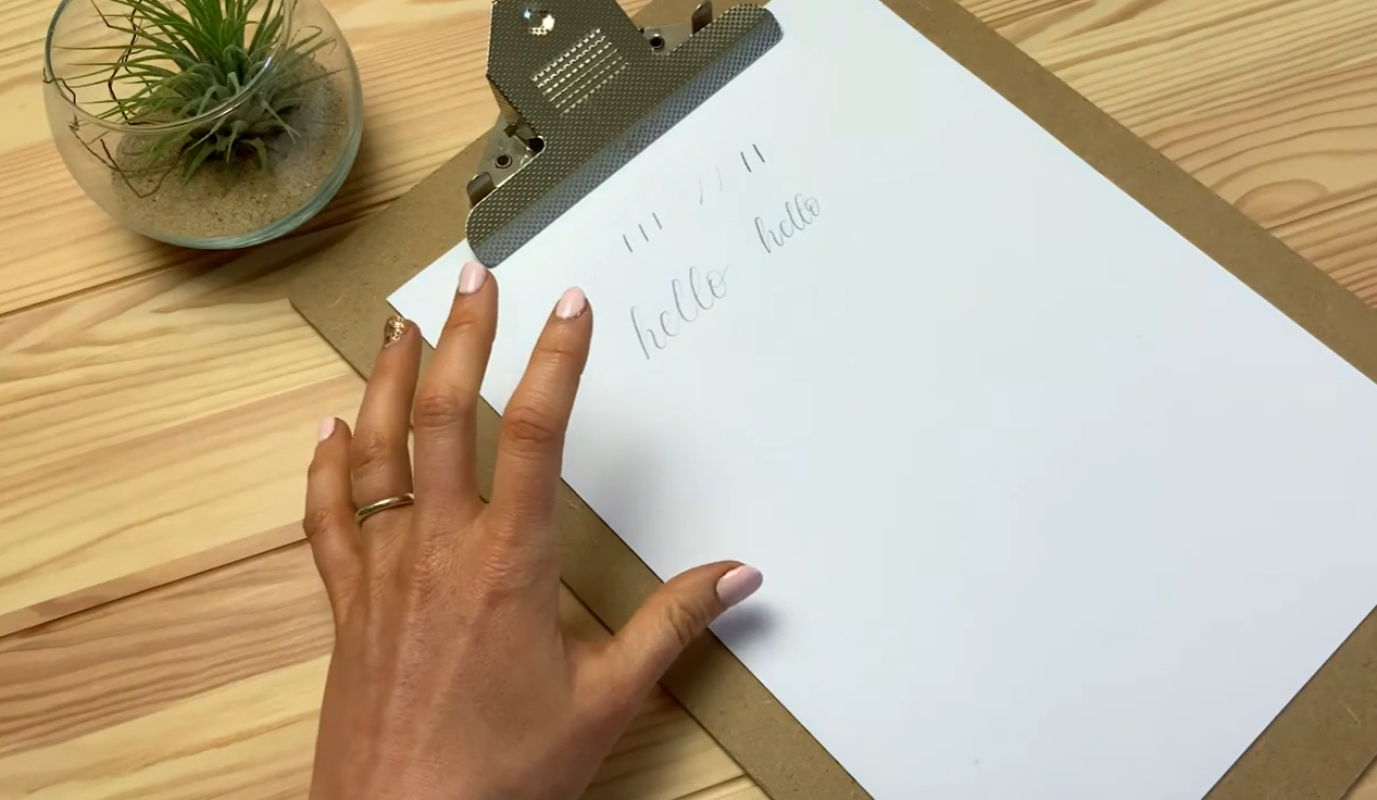 The word "hello" written in modern calligraphy using a pencil, showing thick downstrokes and thin upstrokes created through pressure alone