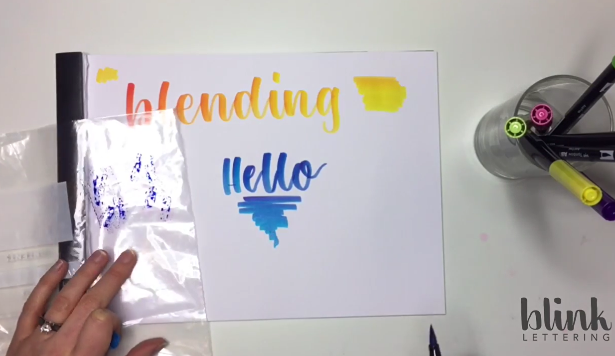 A finished calligraphy piece showing a smooth colour gradient fading from pink and purple through to blue using the sandwich bag blending method