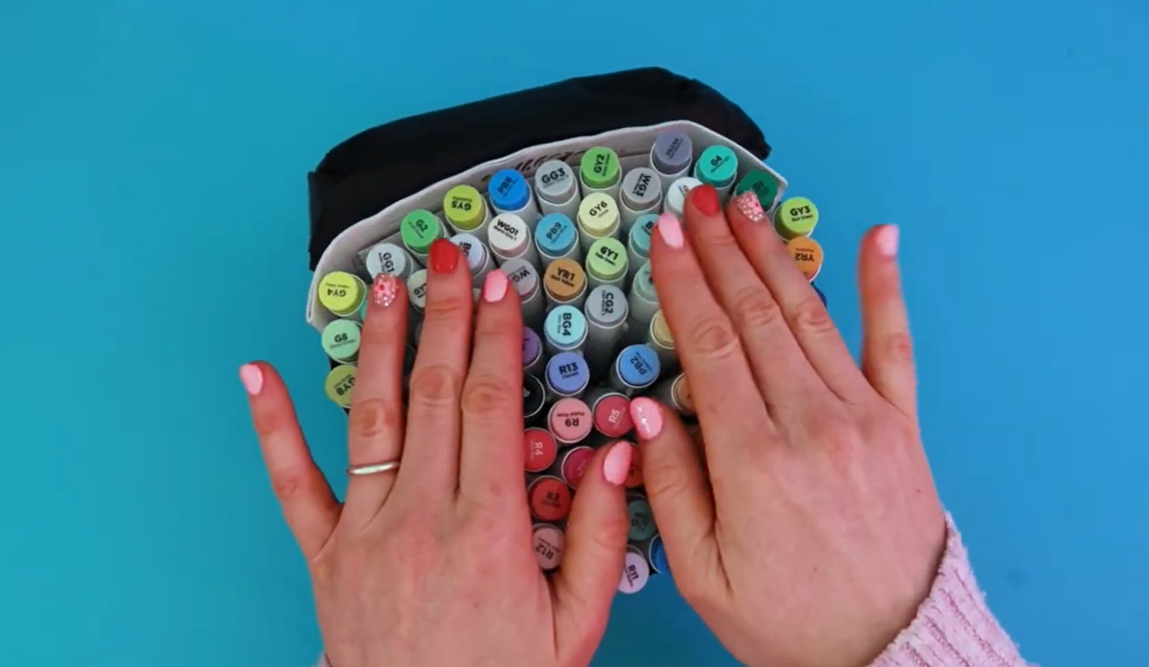 An open Ohuhu marker carry case displaying a wide selection of dual-ended alcohol markers in bold and pastel colours