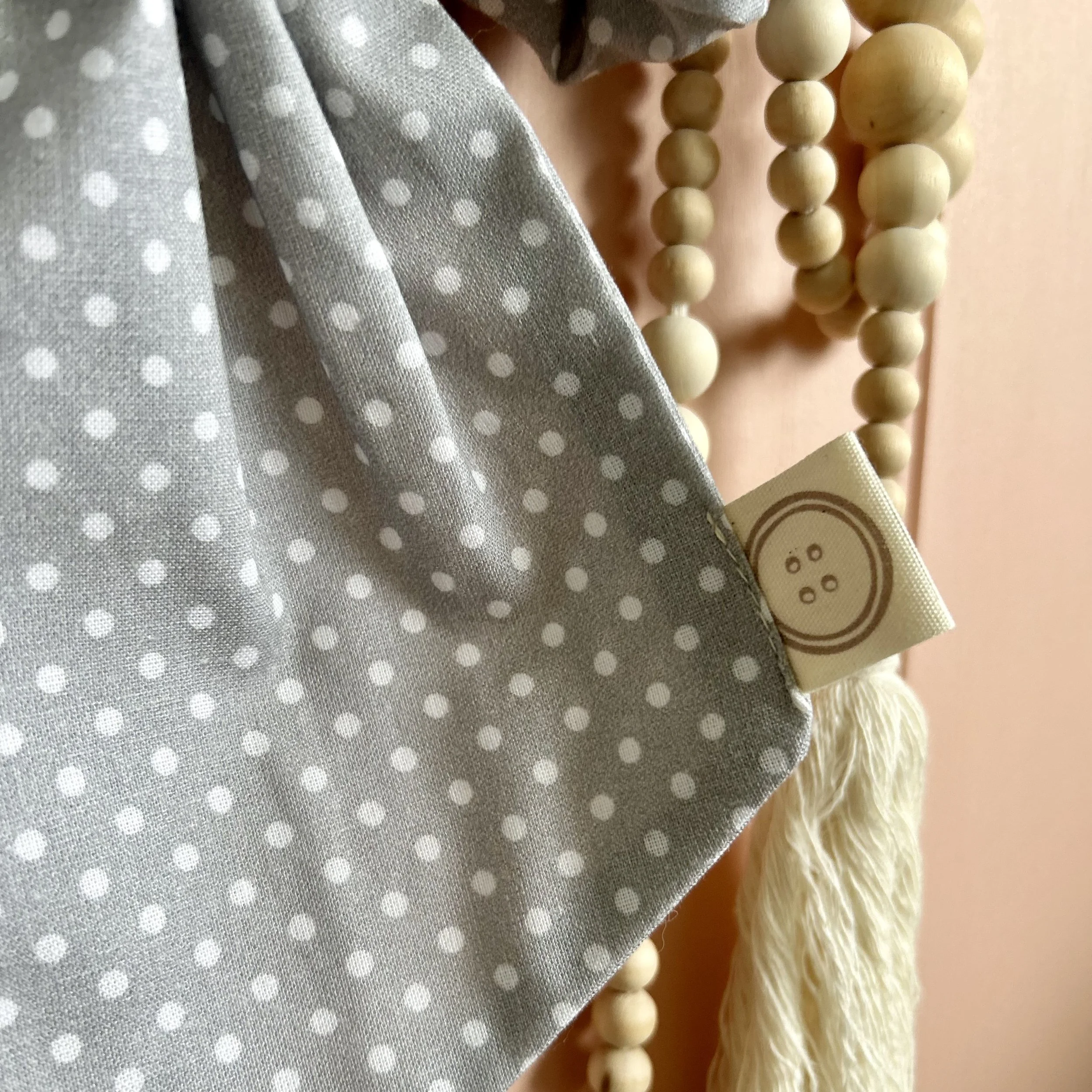Blue/grey detail photo of the cotton fabric. Polka dot pattern and Little Berry Button Tag. Perfect for decoration in a Childs room or nursery.