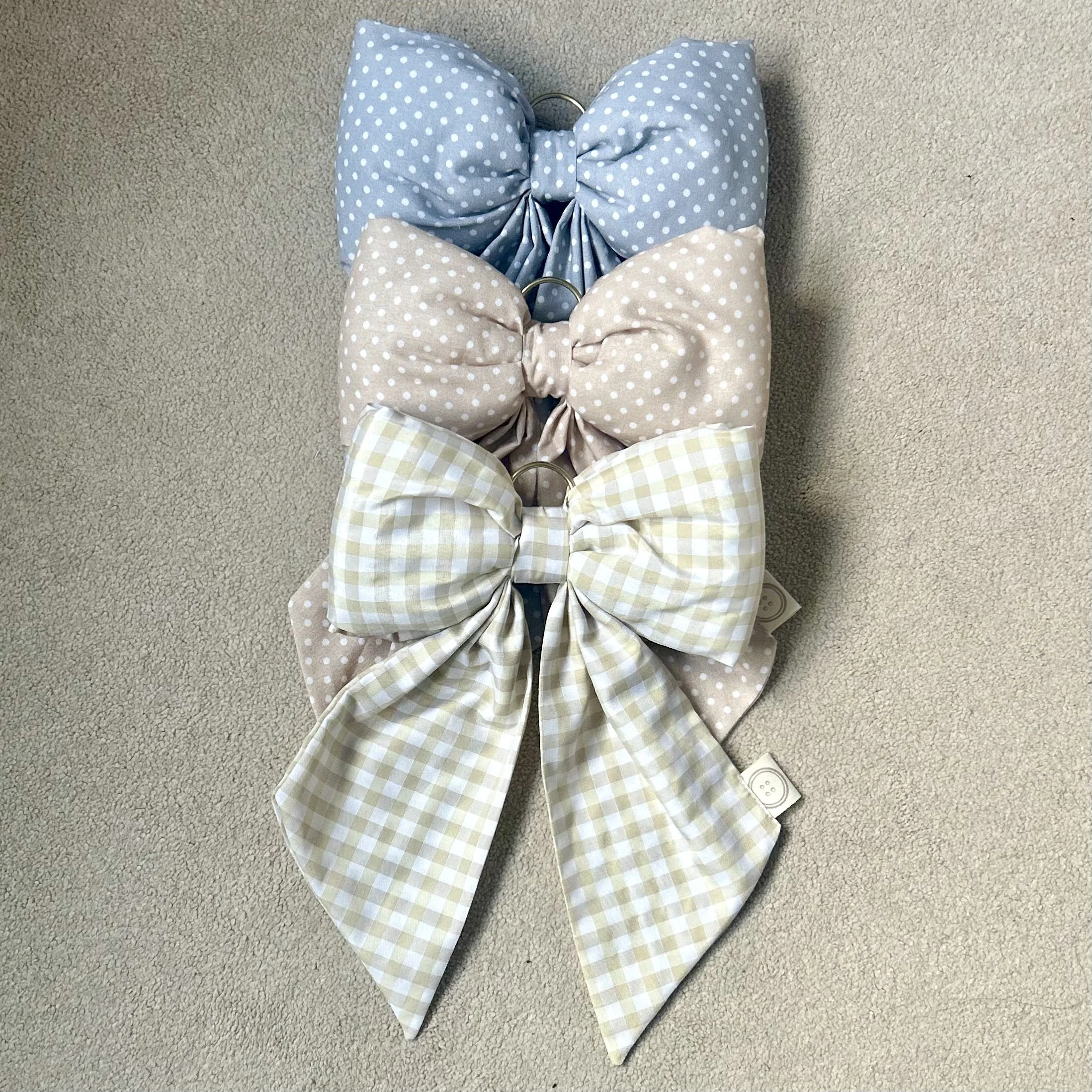 Blue/grey polka dot, Salmon polka dot and cream gingham fabric bow lying together on a beige background. Perfect for nursery decor