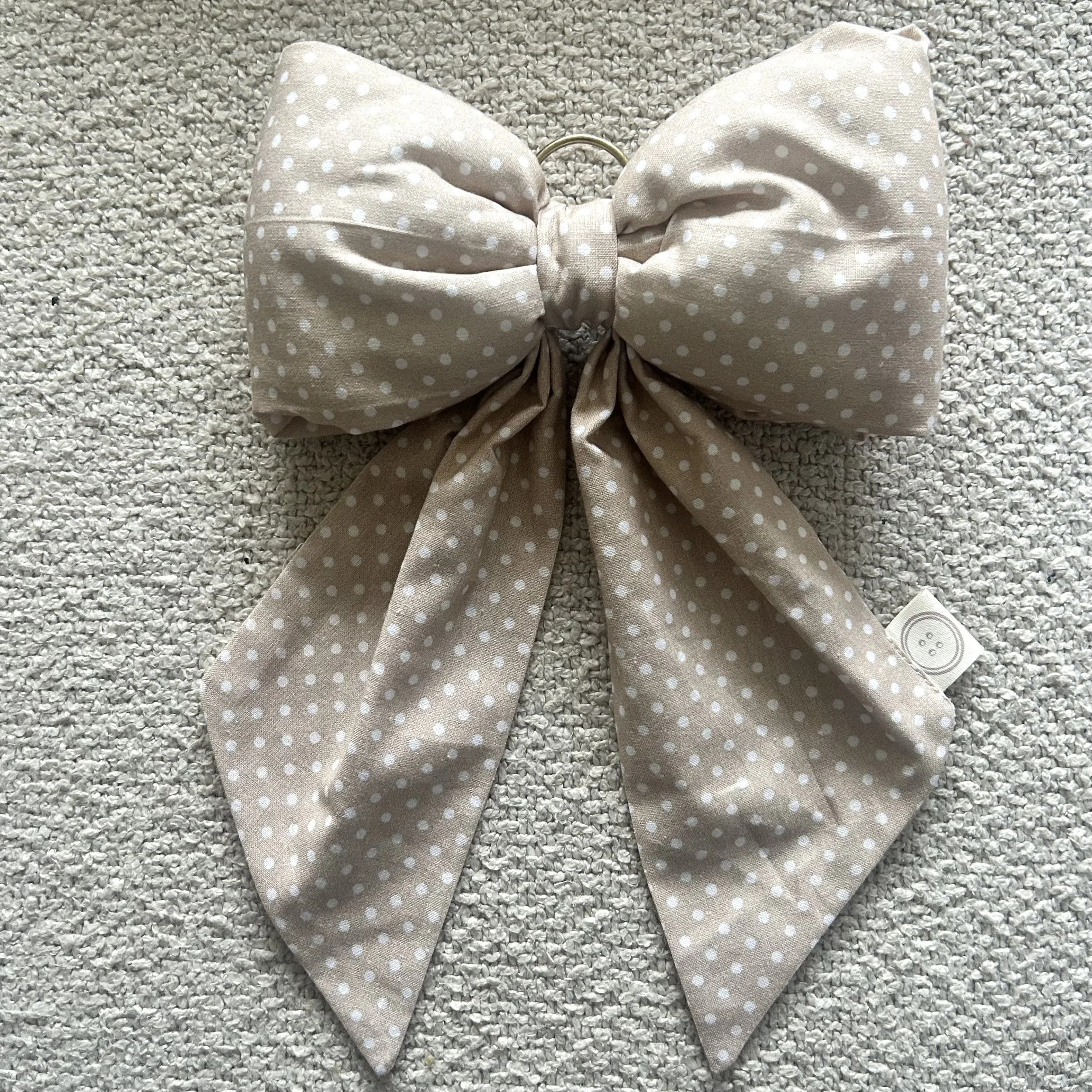 Salmon polka dot fabric bow lying on a beige background. Perfect for nursery decor
