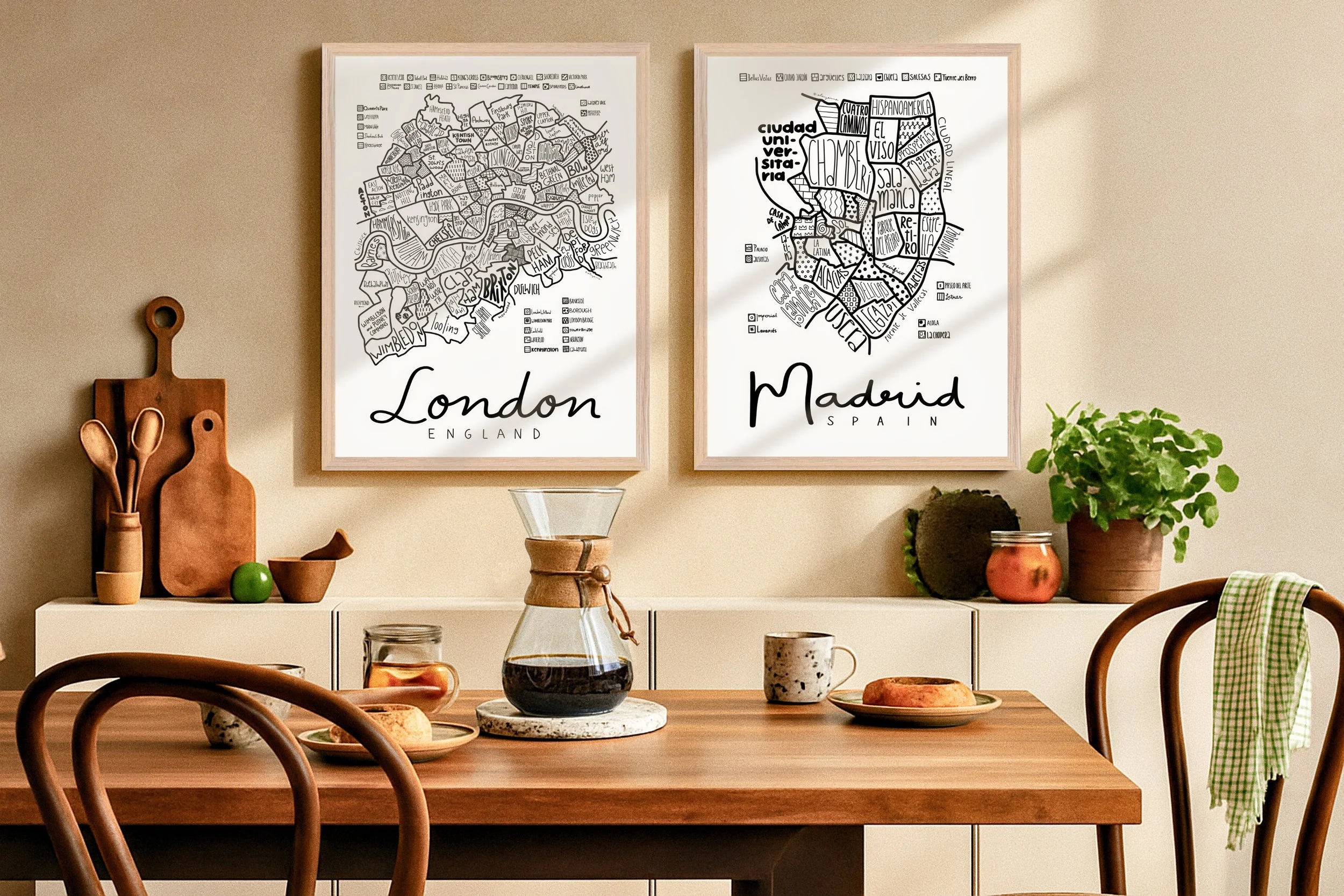 Illustrated map of Madrid in a natural wood frame displayed above a dining table, paired with another framed map.