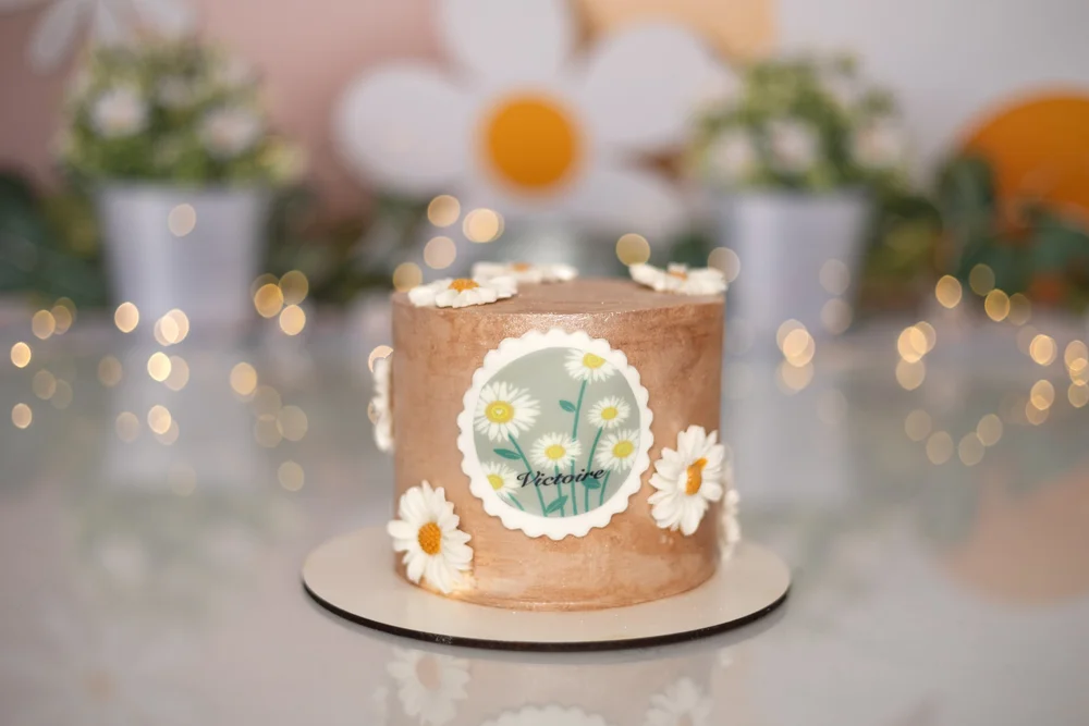 Gâteau d’anniversaire beige décoré de marguerites.