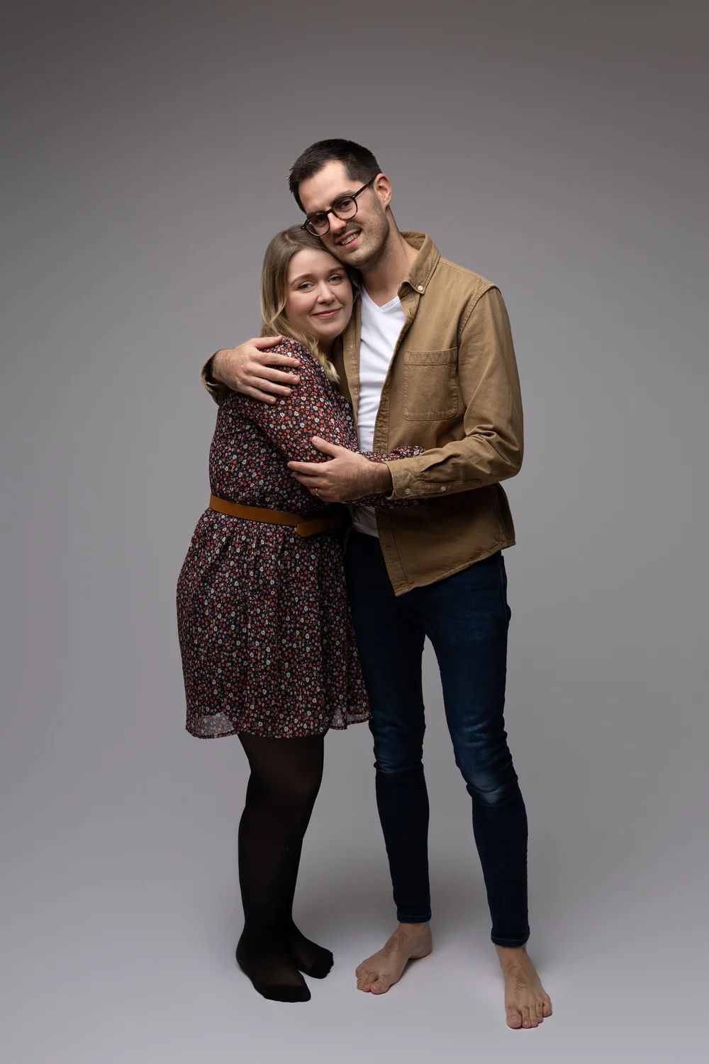 Couple enlacé en studio, sur fond gris.