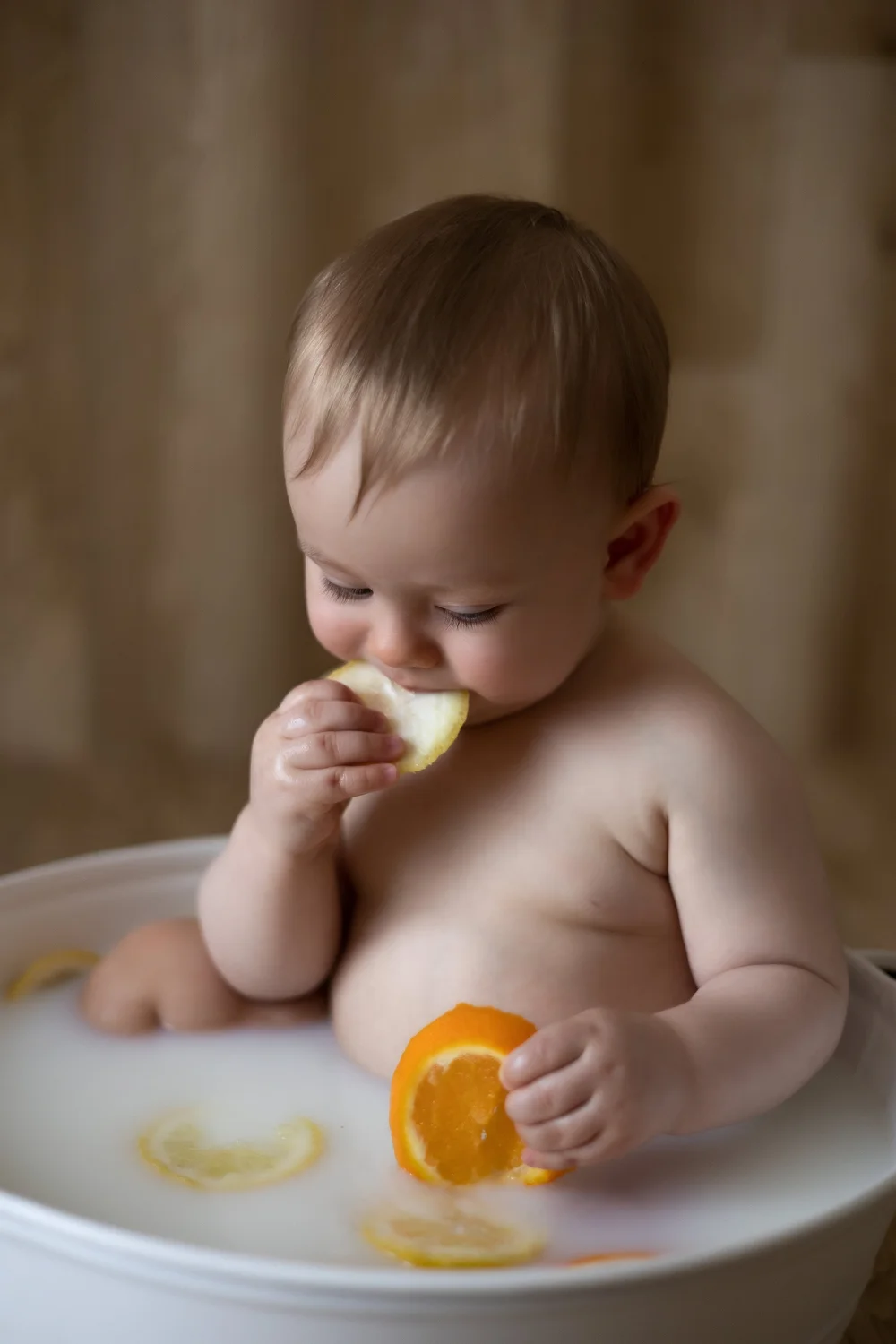 Bébé dans un bain de lait avec des tranches d’orange.
