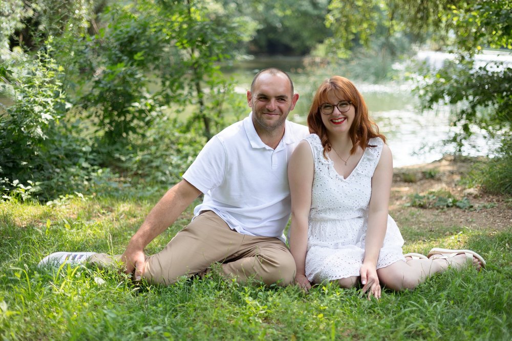 Couple assis dans l’herbe au bord d’un lac.