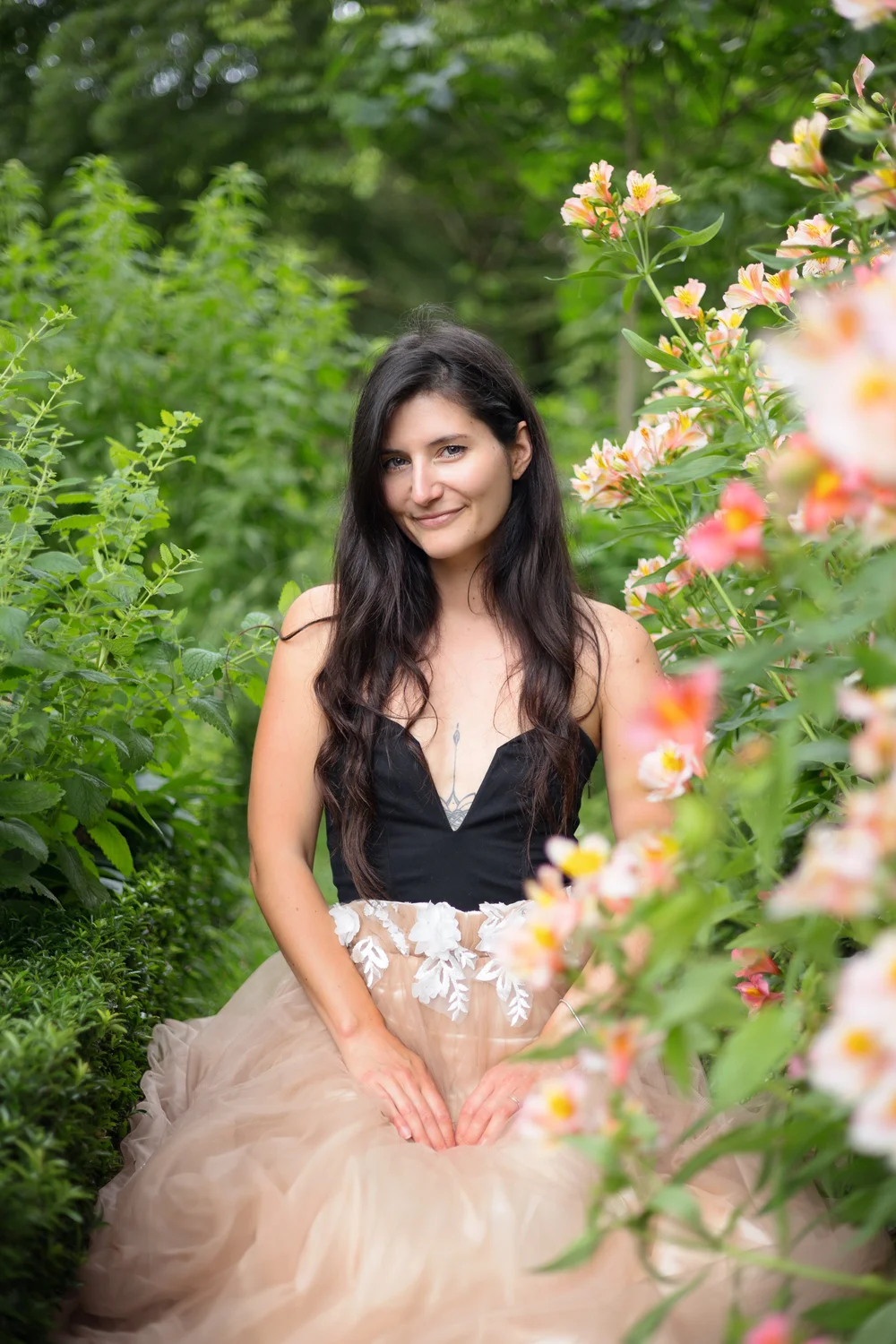 Femme en robe de tulle assise parmi des fleurs.