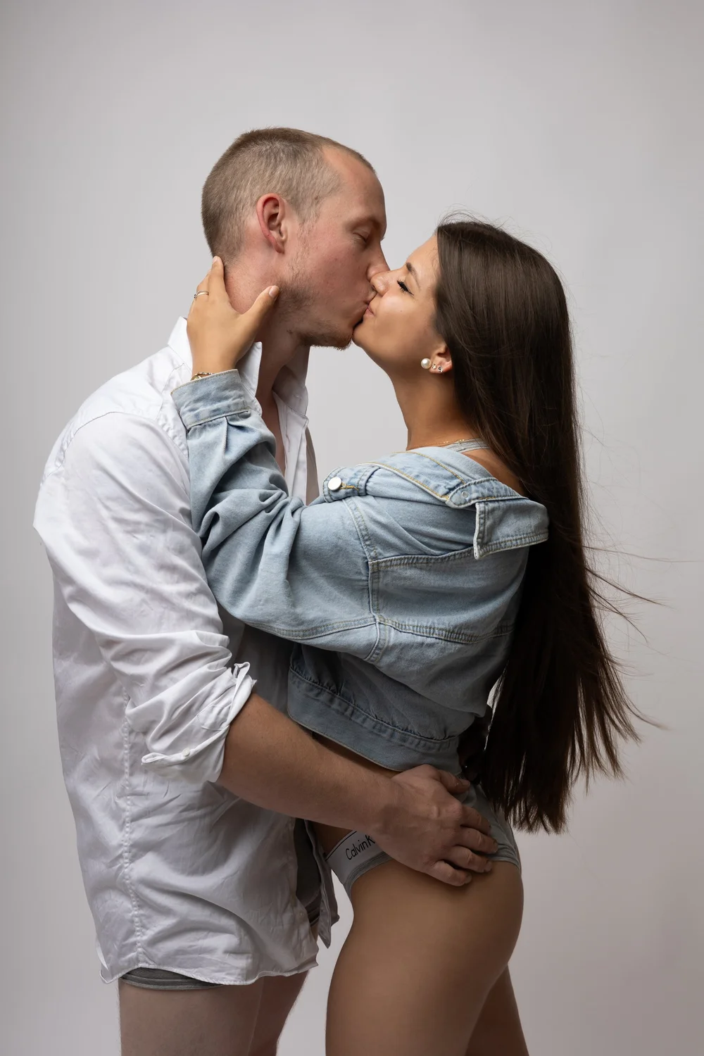Couple s’embrassant en studio, en chemises en jean.