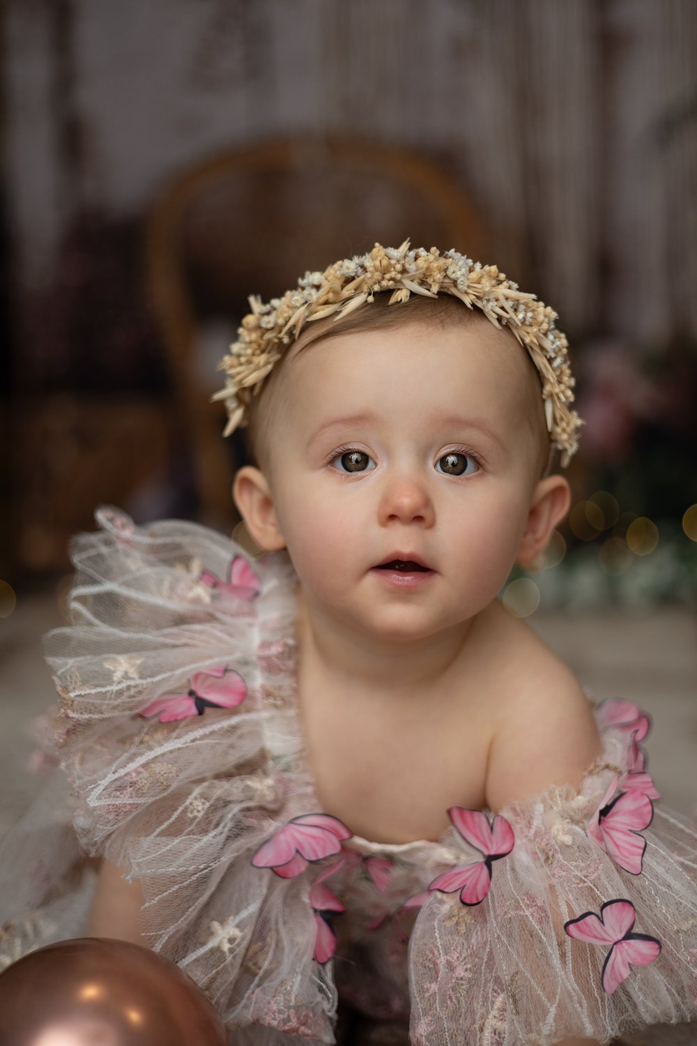 Bébé avec une couronne de fleurs et des papillons, en robe de tulle.