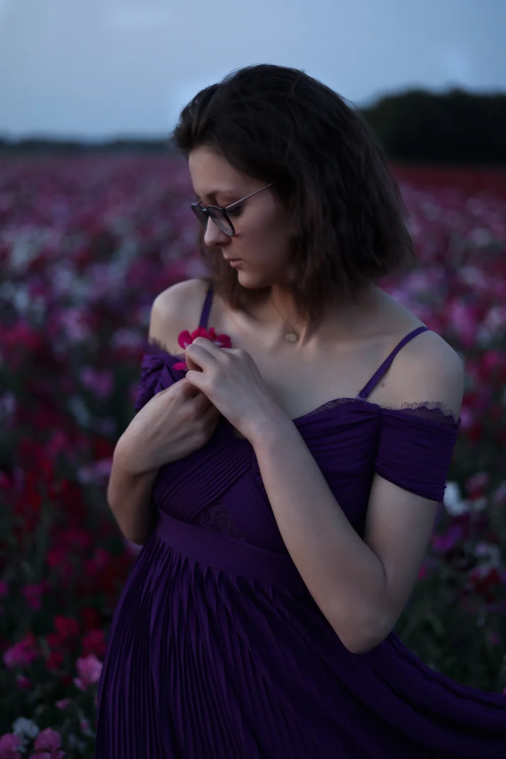 Femme en robe violette dans un champ de fleurs, de profil.
