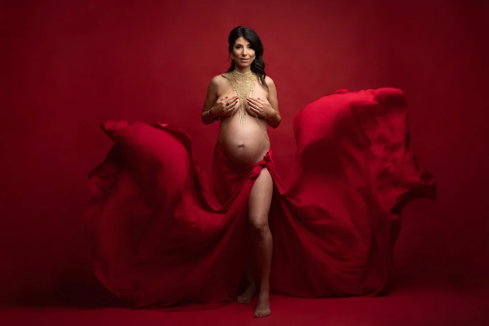 Femme enceinte avec un voile rouge qui vole, sur fond rouge.