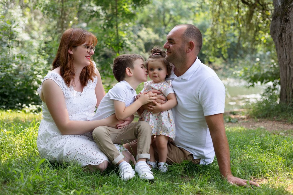 Famille de quatre assise dans l’herbe sous un arbre.