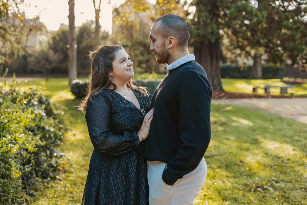 Couple se regardant en souriant dans un parc arboré, au soleil couchant.