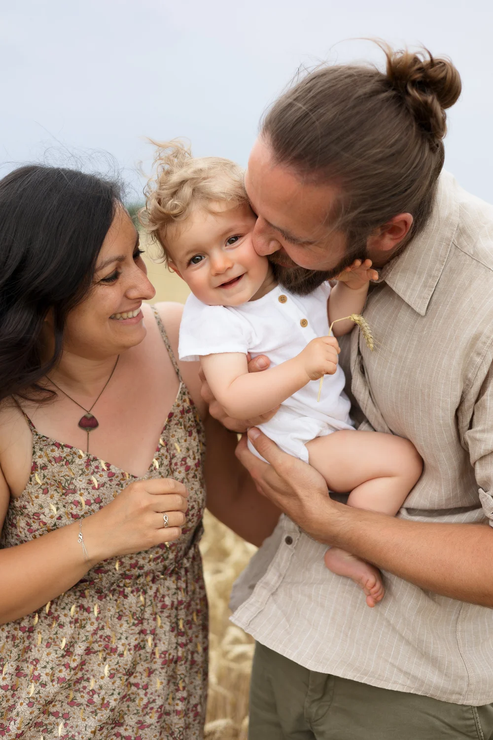 Parents embrassant leur bébé, en extérieur.