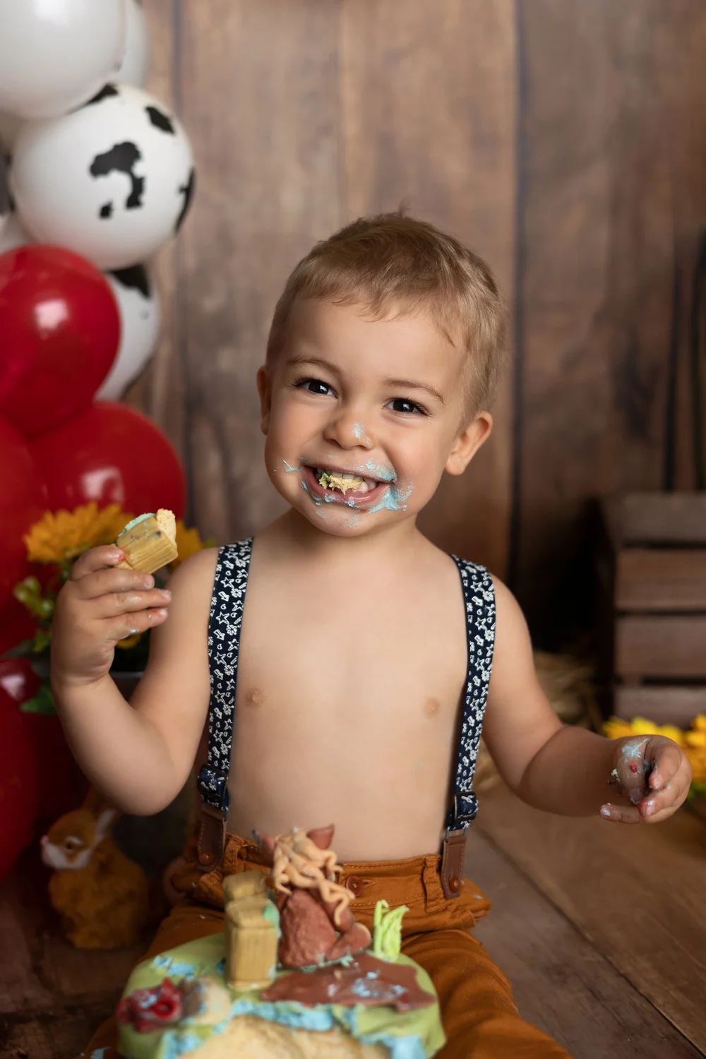 Petit garçon goûtant son gâteau devant un décor de ferme.