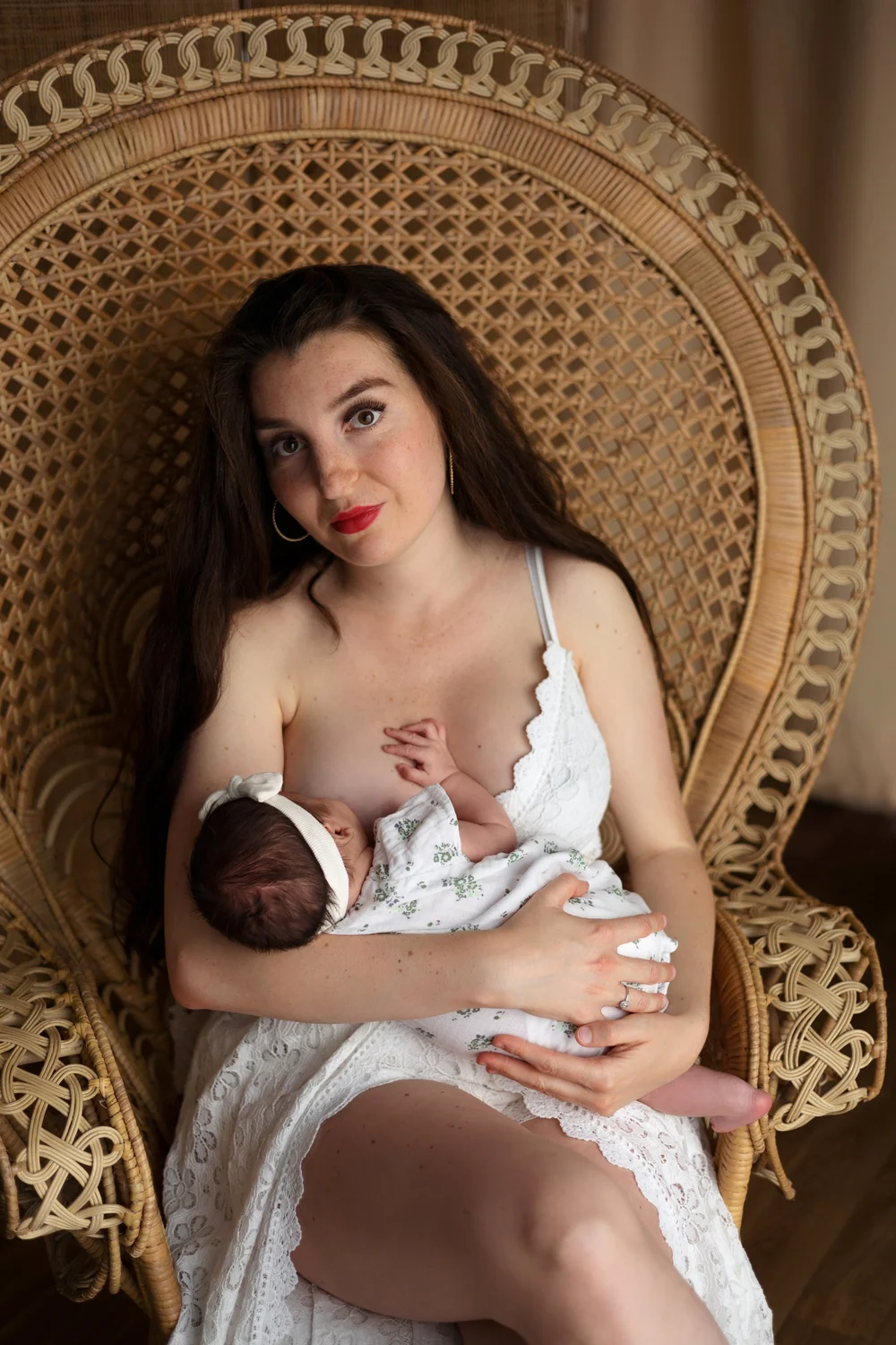 Maman allaitant son nouveau-né dans un fauteuil en rotin.