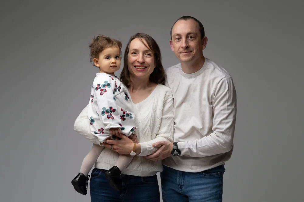 Parents en studio avec leur petite fille en robe fleurie.