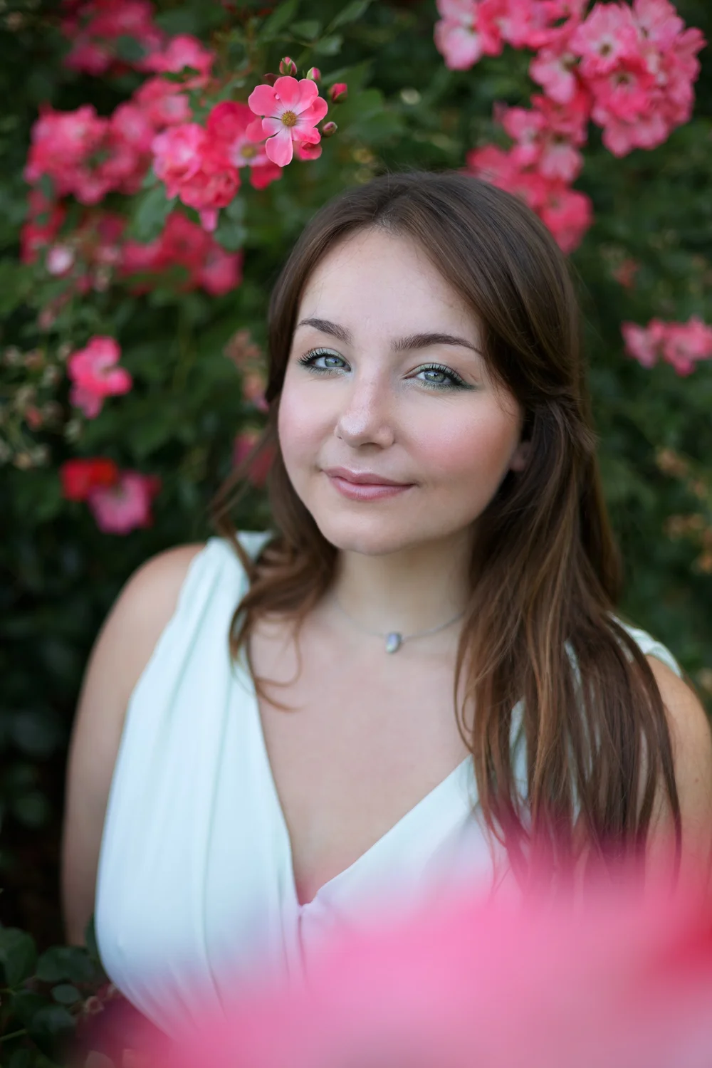 Portrait d’une femme en robe blanche devant des roses.