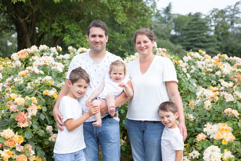 Famille de cinq devant des rosiers en fleurs.
