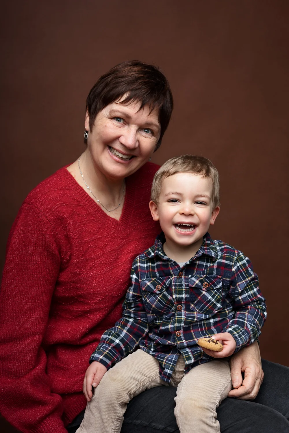 Grand-mère et son petit-fils en studio, sur fond brun.