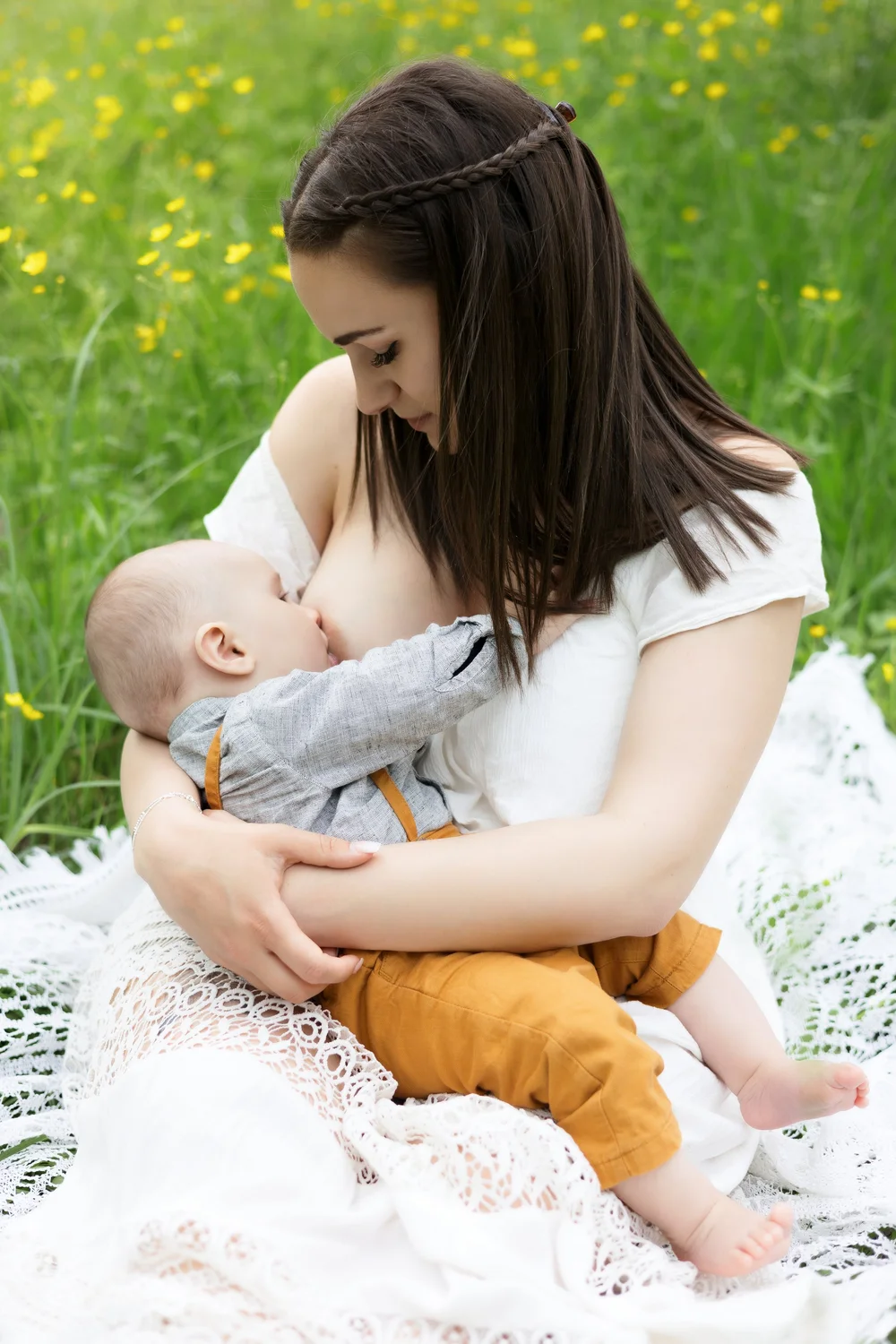 Maman allaitant son bébé dans un pré fleuri.