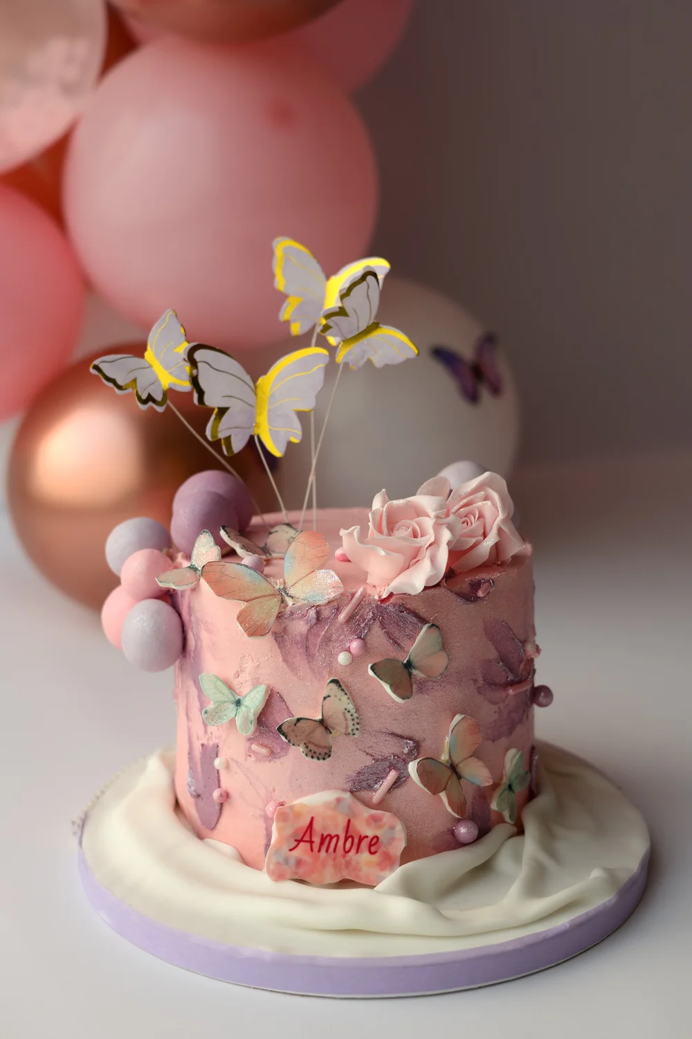 Gâteau d’anniversaire rose décoré de papillons.