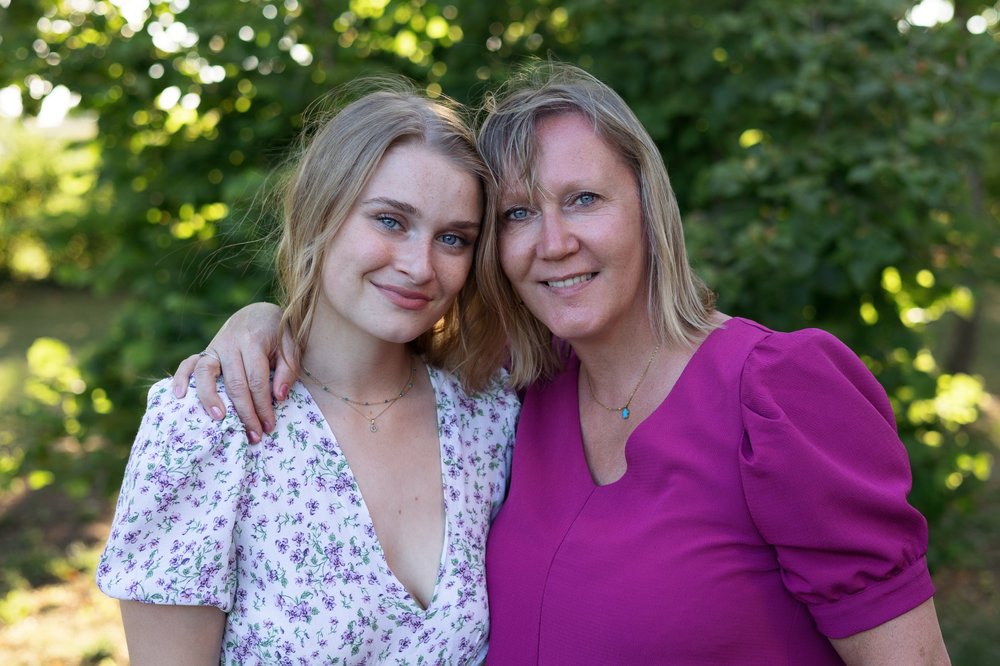 Mère et fille adulte enlacées dans un jardin.