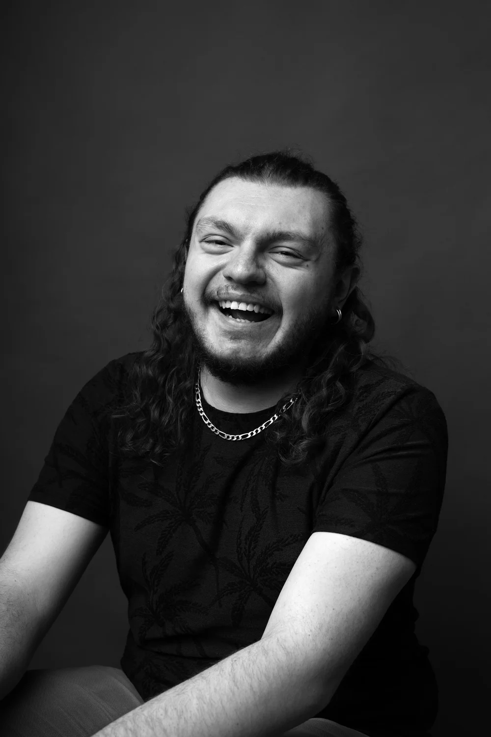 Portrait d’un homme riant, en noir et blanc.