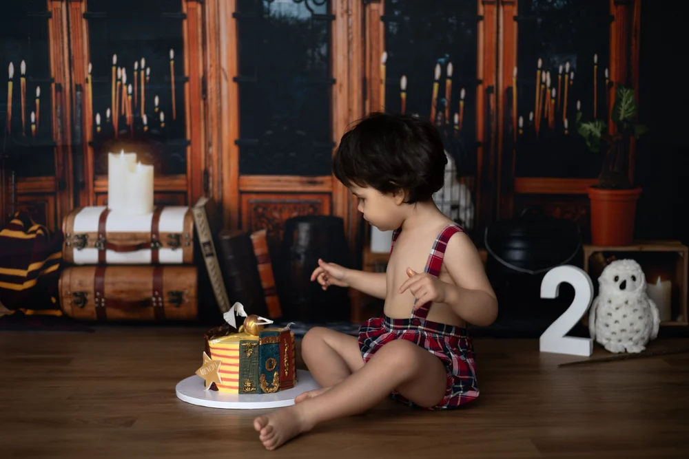 Petit garçon avec son gâteau devant un décor de magicien, chiffre 2.