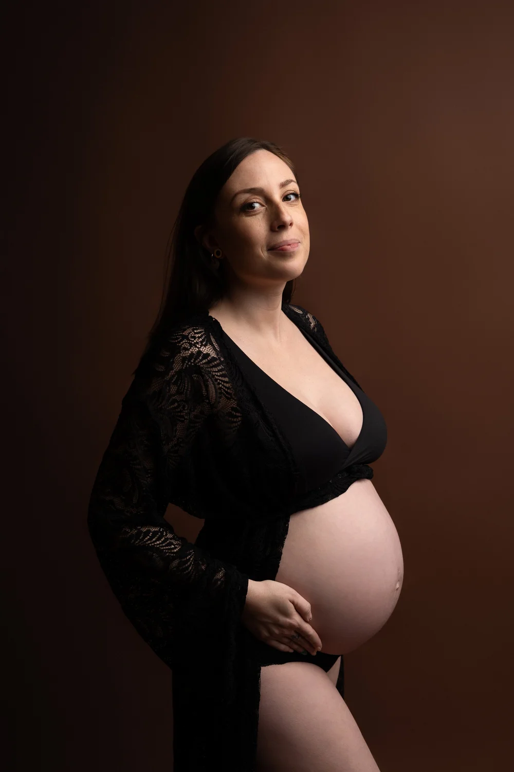 Femme enceinte en lingerie noire et kimono, en studio sur fond brun.