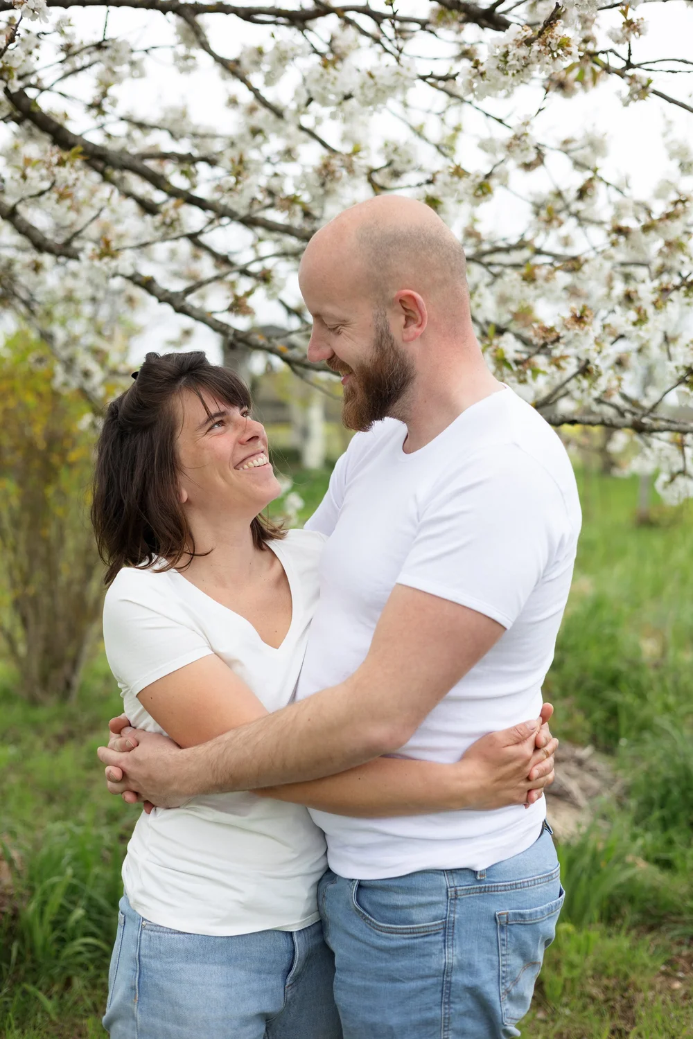 Couple enlacé sous un arbre en fleurs.