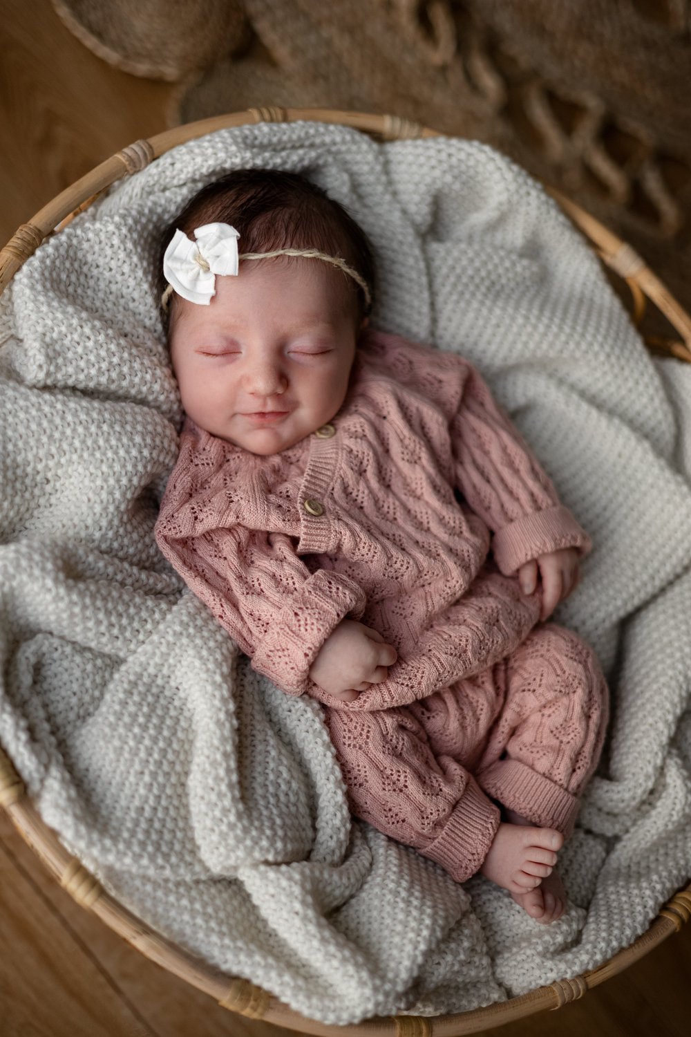 Nouveau-né en tenue rose tricotée endormie dans un panier.