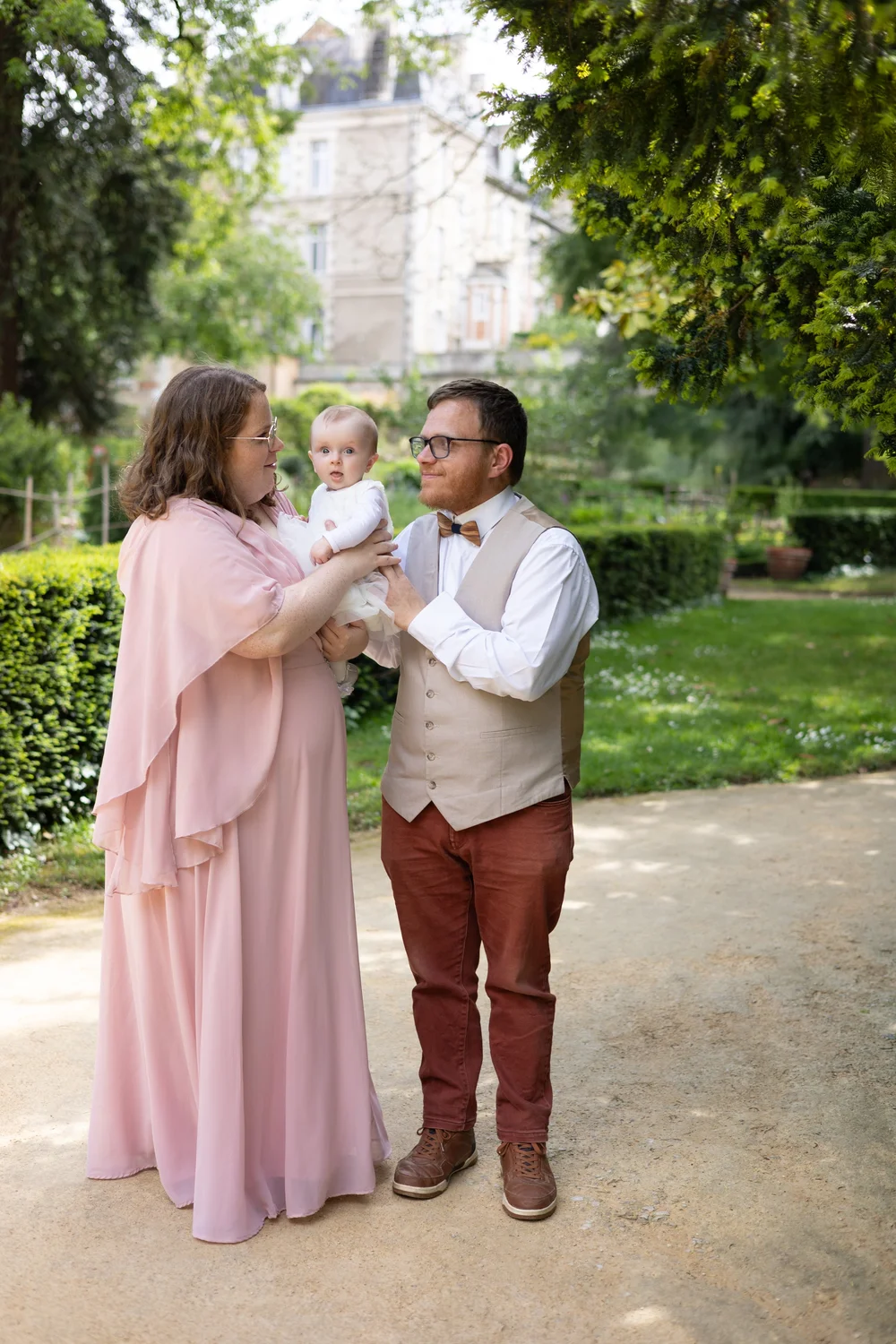 Couple et leur bébé dans l’allée d’un parc, devant un château.