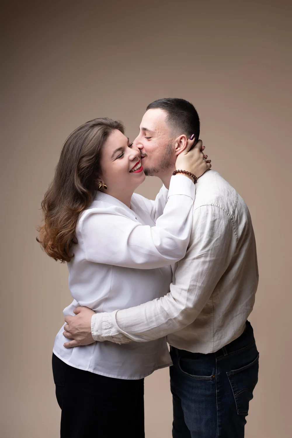 Couple s’embrassant en studio sur fond beige.
