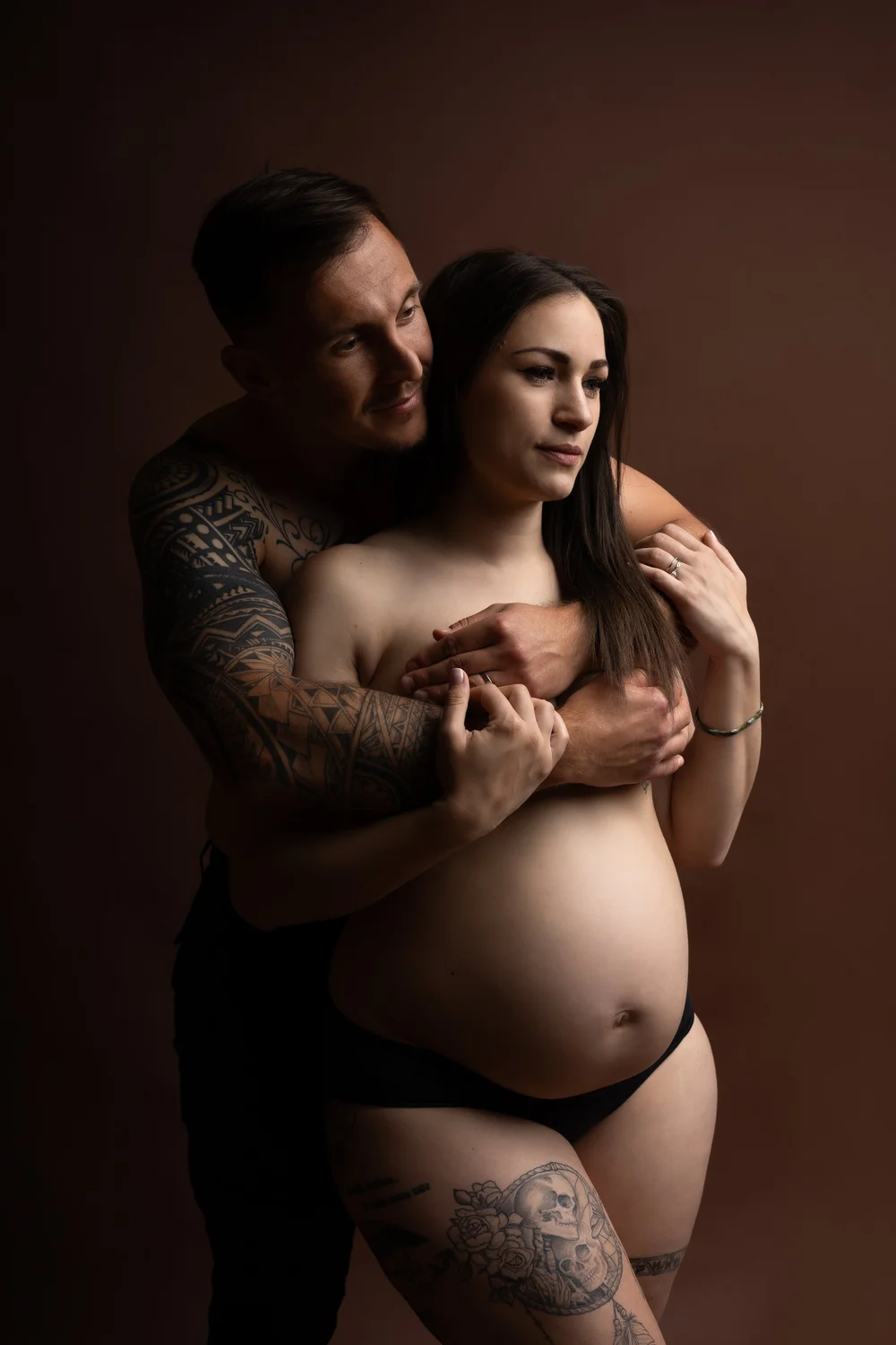 Couple enlacé en studio, sur fond brun.