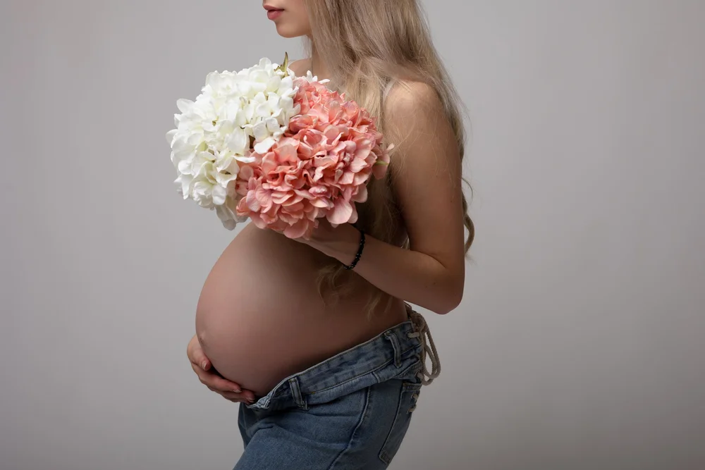 Femme enceinte tenant un bouquet d’hortensias devant son ventre.
