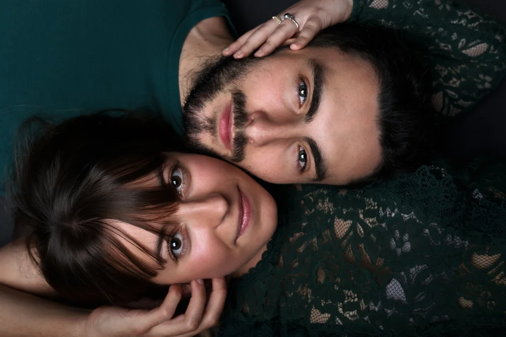 Couple allongé tête contre tête, vu de dessus.