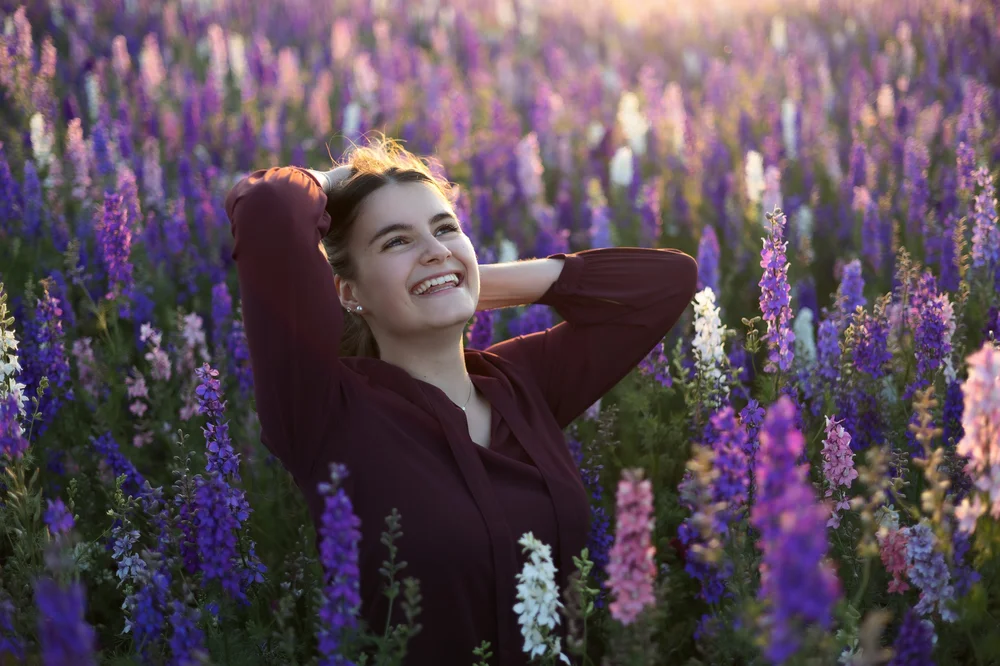 Femme riant dans un champ de fleurs violettes.