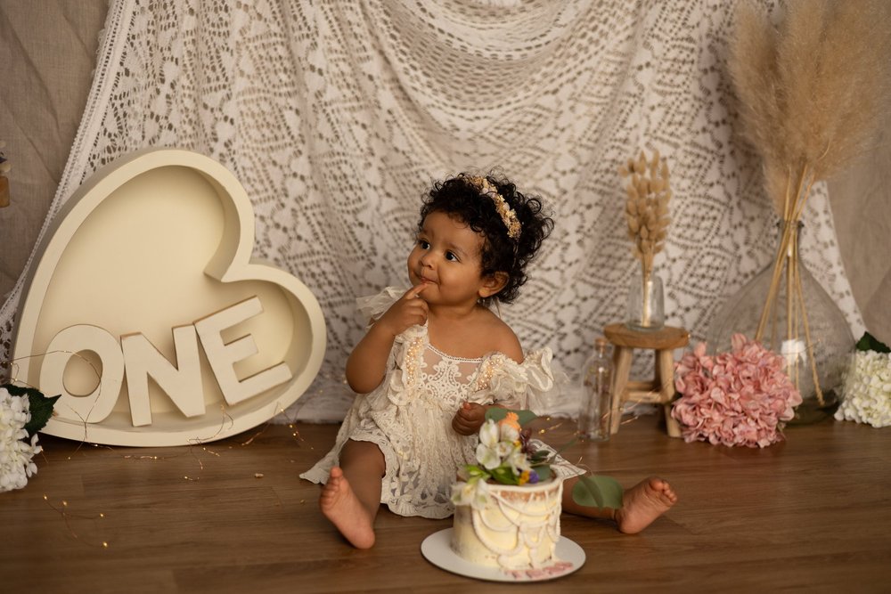Bébé assis avec son gâteau devant un cœur « ONE ».