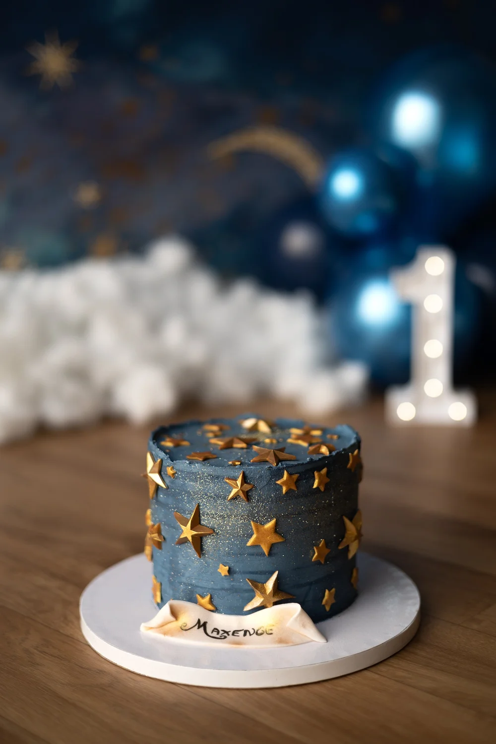 Gâteau bleu étoilé devant un décor de nuages, chiffre 1.