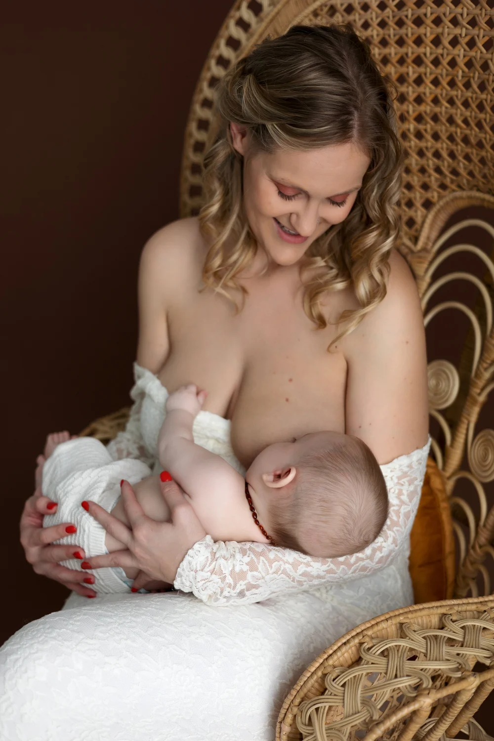 Maman allaitant son bébé dans un fauteuil en rotin.